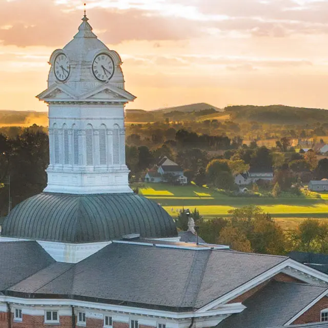 Kutztown University's campus, via aerial view, looking over the iconic Old Main tower, academic buildings, town, and countryside of the scenic Kutztown area
